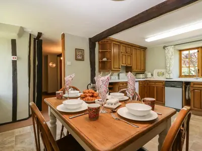 a kitchen with a wooden table with plates and bowls at Lower Court Byre in Kinsham