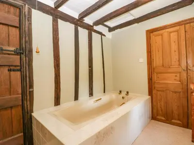 a bath tub in a room with a wooden door at Lower Court Byre in Kinsham