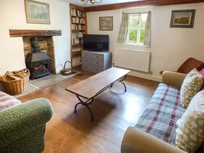 a living room with a couch and a table and a fireplace at Gatehouse in Painscastle