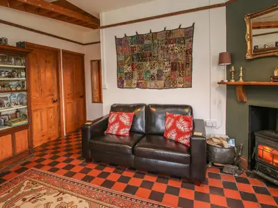 a leather couch in a living room with a fireplace at Hill Brow in Acton Scott