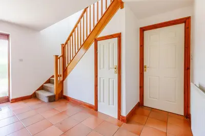 a hallway with a white door and stairs at Byne Brook Cottage in Wistanstow