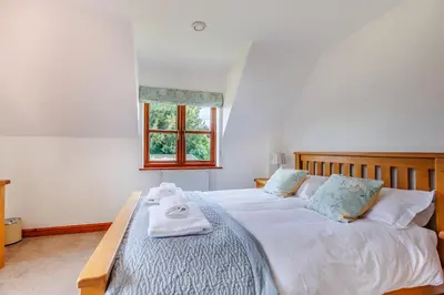 a bedroom with a large bed with towels on it at Byne Brook Cottage in Wistanstow
