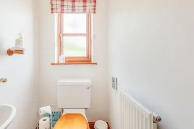a bathroom with a toilet and a sink and a window at Byne Brook Cottage in Wistanstow