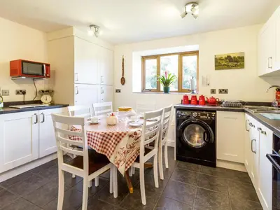 a kitchen with a table and chairs and a dishwasher at Little Cow House in Chirk