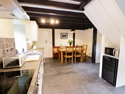 a kitchen with a table and a dining room at Hen Gelligemlyn - The Annexe in Llanfachreth