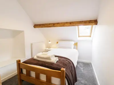 a bedroom with a bed with white sheets and a window at Hen Gelligemlyn - The Annexe in Llanfachreth