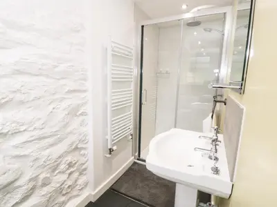a white bathroom with a sink and a shower at Hen Gelligemlyn - The Annexe in Llanfachreth