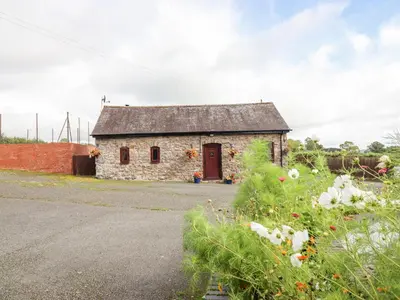 an old stone building with a red door at Bwthyn Ty Newydd in Pont Dolanog