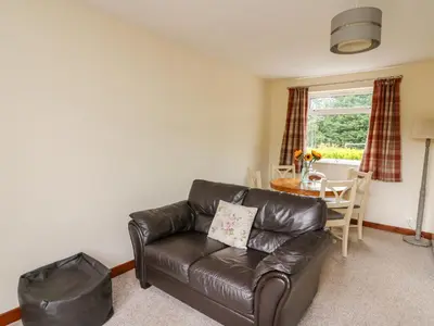 a living room with a leather couch and a table at Red Kite Cottage in Llandrindod Wells
