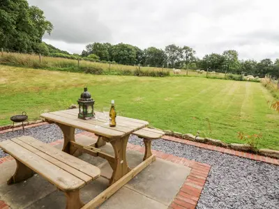 a picnic table with a bottle and a lamp on it at Red Kite Cottage in Llandrindod Wells