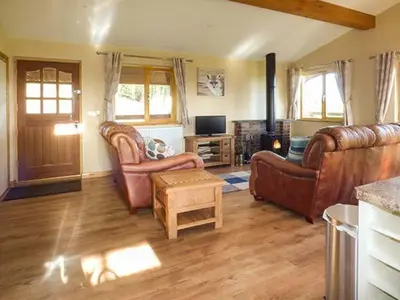 a living room with leather furniture and a television at Valley View Lodge in Trelystan