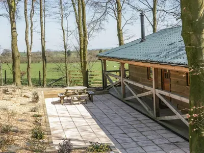 a wooden cabin with a picnic table and a bench at Valley View Lodge in Trelystan