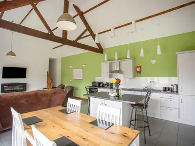 a kitchen and living room with a wooden table in a room at 2 Beacon View Barn in Felindre