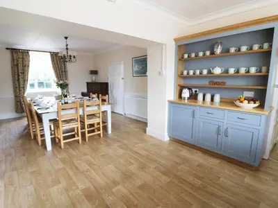 a kitchen and dining room with blue cabinets and a table at Dolau Farmhouse in Llanwnen
