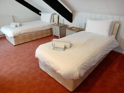 a bedroom with two beds with white sheets at Dolau Farmhouse in Llanwnen