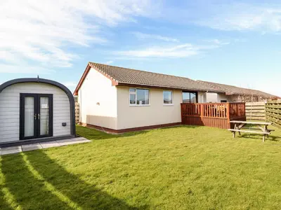 a small white house with a fence and a yard at Sealyons in Fairbourne
