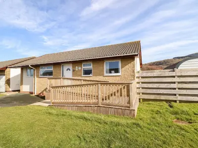a house with a wooden fence in front of it at Sealyons in Fairbourne