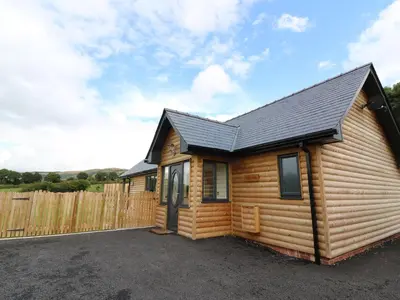 a log cabin with a fence in front of it at Caban Nant Ddu in Nantmel