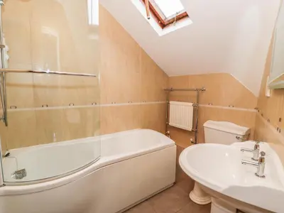 a bathroom with a white tub and a sink at Is Y Deri in Harlech