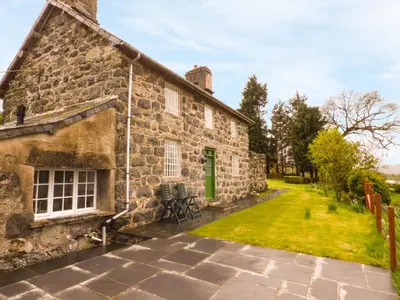 an old stone house with a green door and a yard at Ffynnon Gower in Llangower