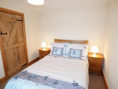 a bedroom with a bed with two lamps and a door at Ffynnon Gower in Llangower