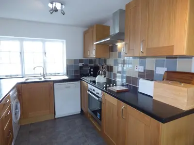 a kitchen with wooden cabinets and a black counter top at Ffynnon Gower in Llangower