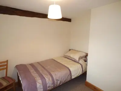 a small bedroom with a bed and a lamp at Ffynnon Gower in Llangower