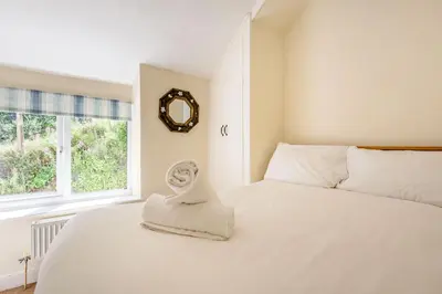 a bedroom with a white bed with a mirror on the wall at Kynaston Cottage in Aberdyfi