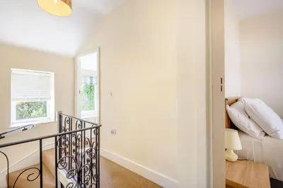 a white bedroom with a bed and a window at Kynaston Cottage in Aberdyfi