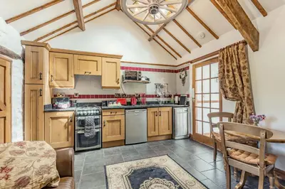 a kitchen with wooden cabinets and a table and chairs at Y Becws in Llanbedr