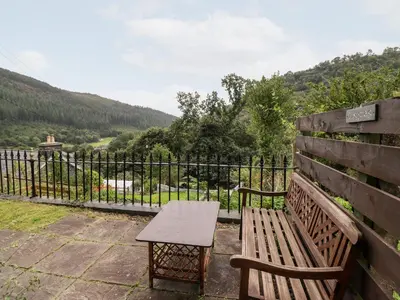a wooden bench sitting next to a fence at 2 Isygraig in Corris