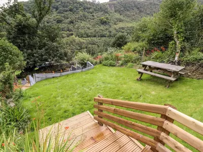 a wooden bench sitting in the grass with a picnic table at 2 Isygraig in Corris