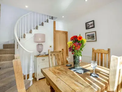 a dining room with a wooden table with a vase of flowers at Bro Dawel in Dolgellau