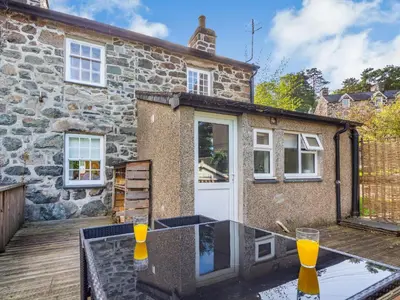 a stone cottage with a table in front of it at Bro Dawel in Dolgellau