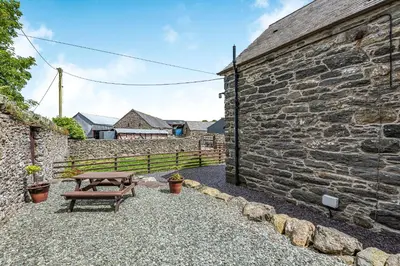 a picnic table in front of a stone wall at Waedog Bach in Llanfor