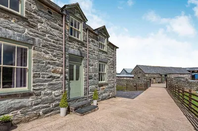 a stone house with a green door and a driveway at Waedog Bach in Llanfor