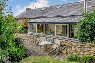 a stone house with a table and chairs outside at Hwylfa'r Groes in Dyffryn
