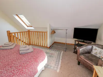 a living room with a bed and a television at Bryn Melyn Artist's Cottage in Llanelltyd