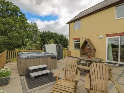 a patio with a hot tub and a table and chairs at Foxes Meadow in Llandrindod Wells