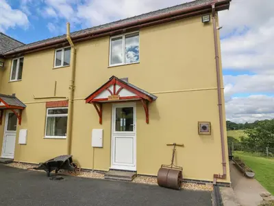 a yellow house with a dog in front of it at Foxes Meadow in Llandrindod Wells