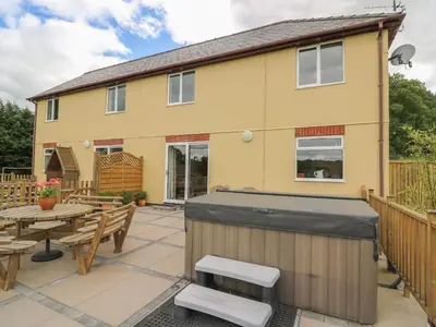 a backyard with a hot tub and picnic tables at Pheasant Wood in Llandrindod Wells