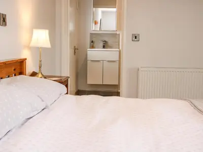a bedroom with a large white bed with a lamp at Bryn Caer in Chirbury