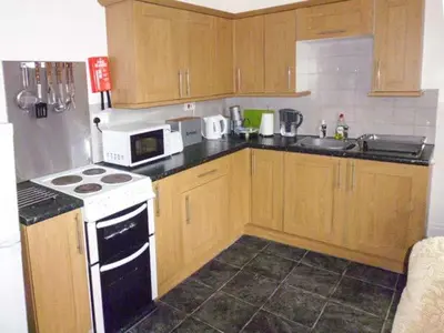 a kitchen with wooden cabinets and a white stove top oven at Harley Apartment in Bishops Castle