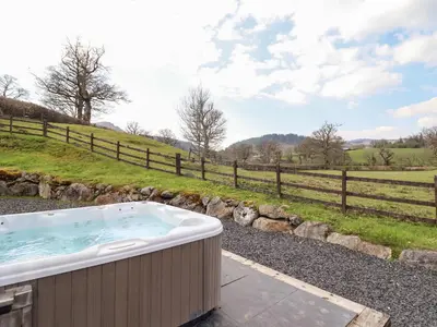 a hot tub with a view of a field at Beudy Bach Barn in Llanuwchllyn