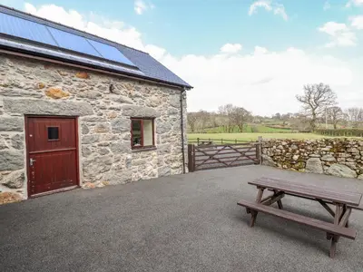 a bench next to a stone building with a barn at Beudy Bach Barn in Llanuwchllyn