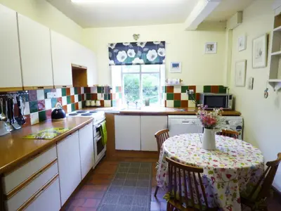a kitchen with a table with a vase of flowers on it at Arllen Fawr in Pen-y-bont-fawr