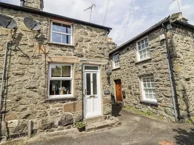 a stone cottage with a white door and windows at Cae Tanws Bach in Dolgellau