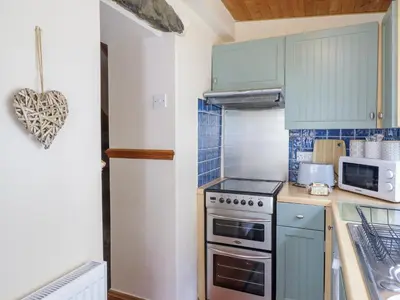 a kitchen with blue cabinets and a stove top oven at Cae Tanws Bach in Dolgellau