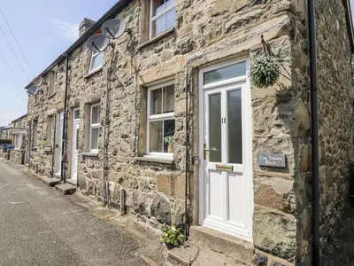a stone building with a white door on a street at Cae Tanws Bach in Dolgellau