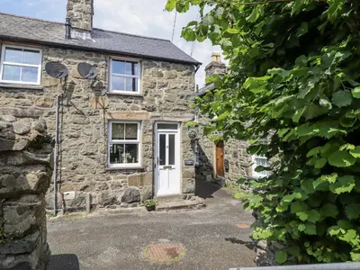 an old stone cottage with a white door at Cae Tanws Bach in Dolgellau